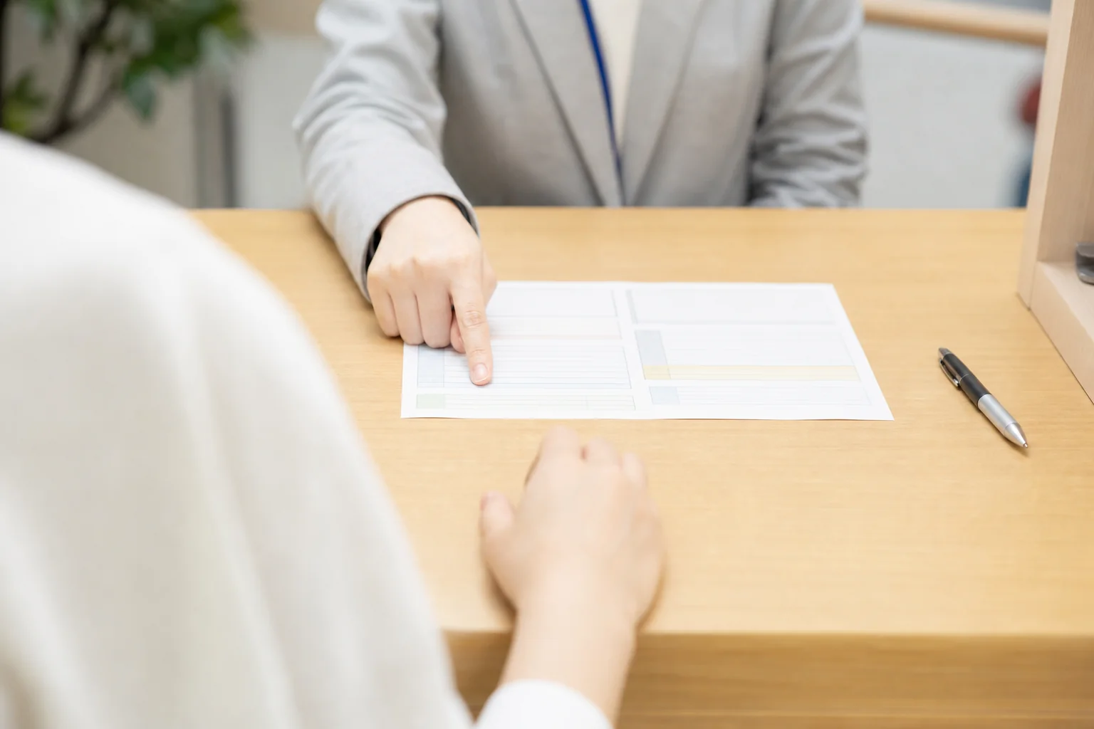 フリーターがハローワークの窓口で求人票を見ながら職員に相談する時の、カウンターの上の書類と手元